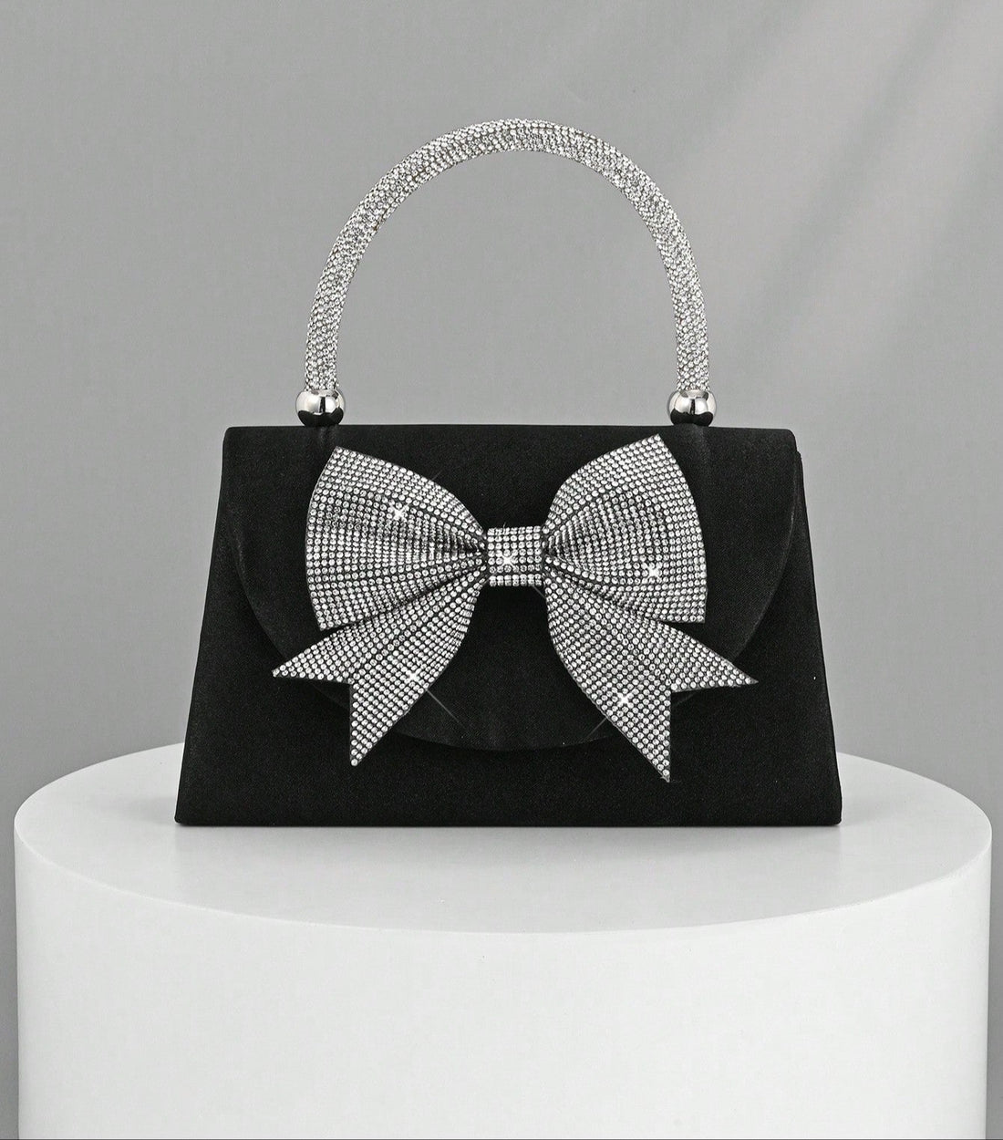 Step out in style with this Elegant Black Satin Clutch, featuring a sparkling rhinestone bowknot that adds just the right amount of glam. Perfect for parties and weddings, this luxury evening handbag is your go-to for keeping essentials close while turning heads. Its sleek design and dazzling detail make it a playful yet sophisticated accessory that brightens any outfit. Ready to dazzle? This clutch is your new best party buddy!