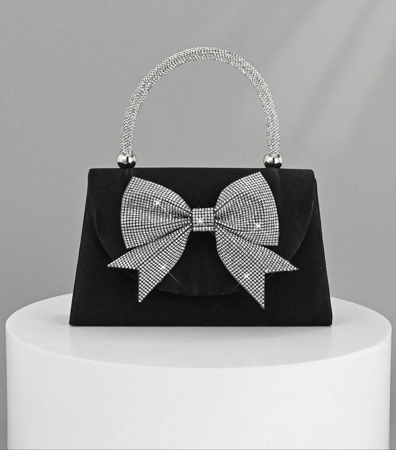 Step out in style with this Elegant Black Satin Clutch, featuring a sparkling rhinestone bowknot that adds just the right amount of glam. Perfect for parties and weddings, this luxury evening handbag is your go-to for keeping essentials close while turning heads. Its sleek design and dazzling detail make it a playful yet sophisticated accessory that brightens any outfit. Ready to dazzle? This clutch is your new best party buddy!