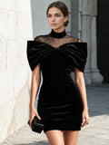 Front view of black velvet-look mini party dress with sheer mesh neckline and oversized bow