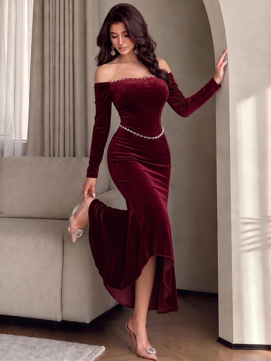 Full front view of a model in a burgundy velvet off-shoulder mermaid evening gown with pearl neckline and waist trim
