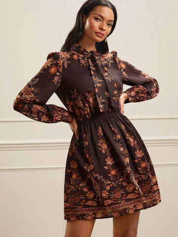 Embrace the warmth of the seasons with this elegant floral print dress, a versatile earth-tone essential designed for seamless transitions between spring and autumn. Featuring a sophisticated tie collar and graceful lantern sleeves, this piece perfectly captures a refined, vintage-inspired aesthetic. The delicate botanical patterns in rich, muted tones offer a timeless appeal that complements any landscape, while the lightweight, high-quality fabric ensures a comfortable and flattering flow. Whether paired 