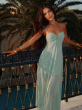 Front view of mint green spaghetti strap gathered bodice maxi dress on balcony