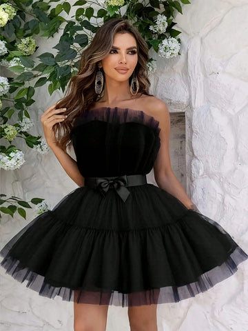 Make a statement in this show-stopping black tulle mini dress that's equal parts sophisticated and fun. The off-the-shoulder neckline offers a flirty peek of skin, while the delicate bow detail adds a touch of whimsy to your look. Crafted from airy tulle fabric, this dress moves beautifully and photographs like a dream—whether you're dancing at a wedding, celebrating at a party, or turning heads at any formal occasion. Effortlessly chic and undeniably elegant, this is the dress that makes you feel absolutel