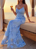 Seated front view of blue floral appliqué spaghetti strap maxi dress