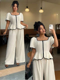 Elevate your spring and summer wardrobe with this sophisticated plus-size two-piece set. The blouse features a chic square neckline, puff sleeves, and elegant contrast binding that adds visual interest. A colorblock design in crisp white creates a modern, polished look perfect for the office or special occasions. 
