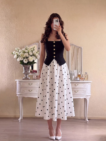 Front mirror view of black square-neck gold-button top and white polka-dot A-line midi skirt set
