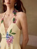 Close-up front view of pale yellow floral halter midi dress with appliqué straps and illusion V-neck