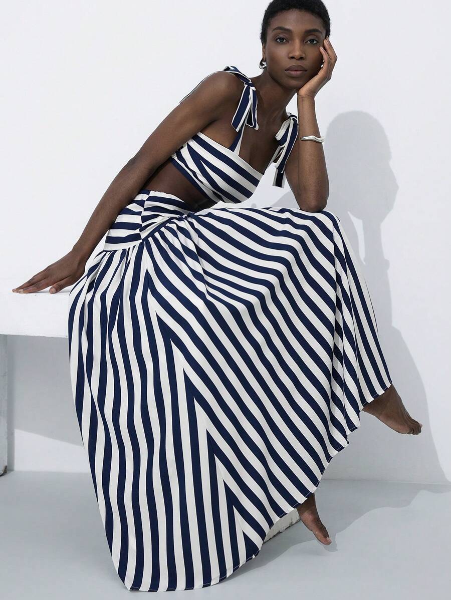 Turn heads at your next getaway with this chic two-piece set that effortlessly transitions from beach days to evening soirées. The strapless striped crop top pairs perfectly with a high-waisted skirt featuring a sultry side split—giving you that perfect balance of sophistication and flirtation. Whether you're sipping cocktails poolside or dancing under the stars, this set delivers instant glamour without the fuss. Comfortable, versatile, and undeniably stylish.