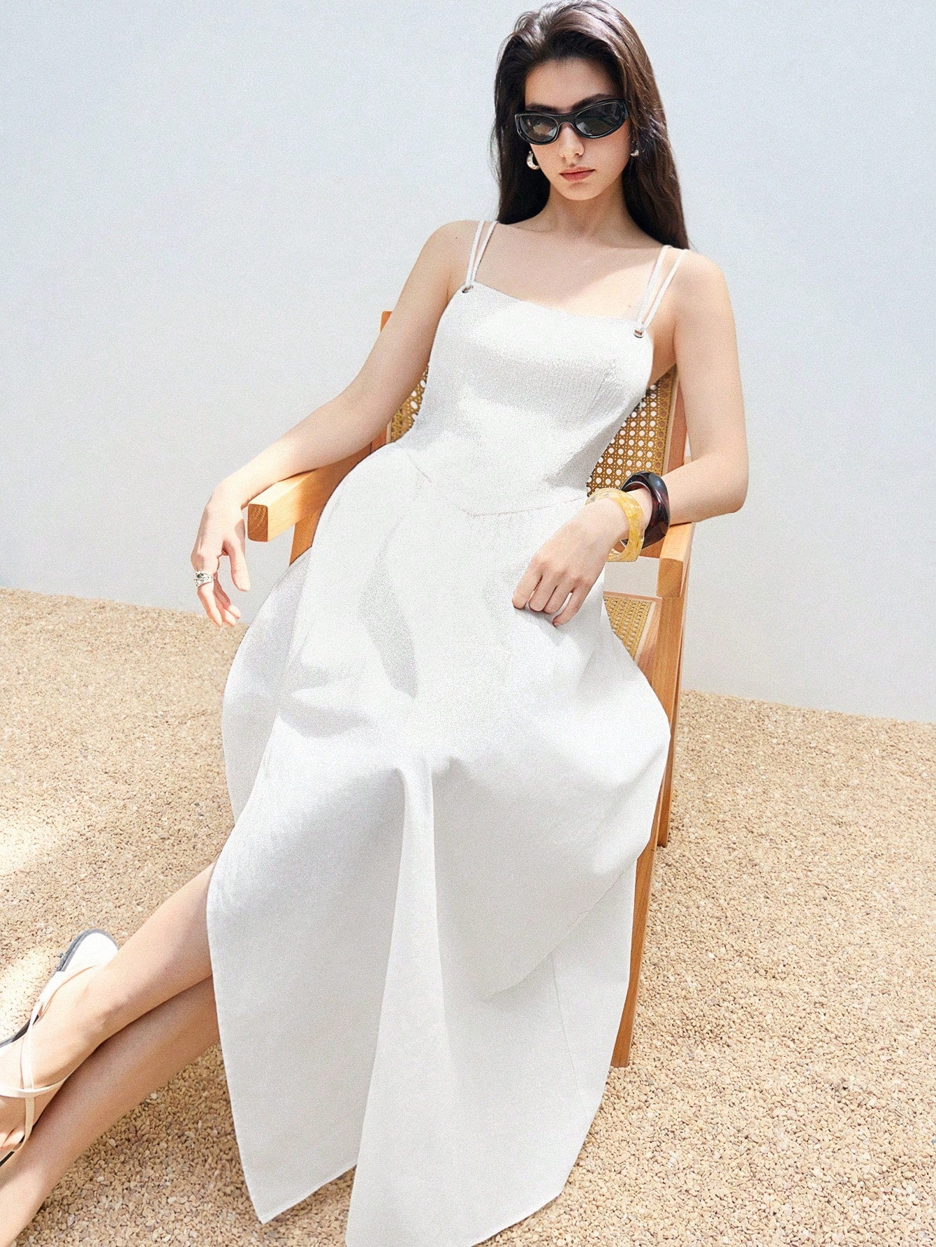 Step into summer with this playful white suspender dress featuring delicate pleated fabric and a breezy high slit. Its bohemian charm and casual chic style make it perfect for sunny days and spontaneous adventures. Light, elegant, and effortlessly stylish, this dress adds a fun twist to your warm-weather wardrobe.