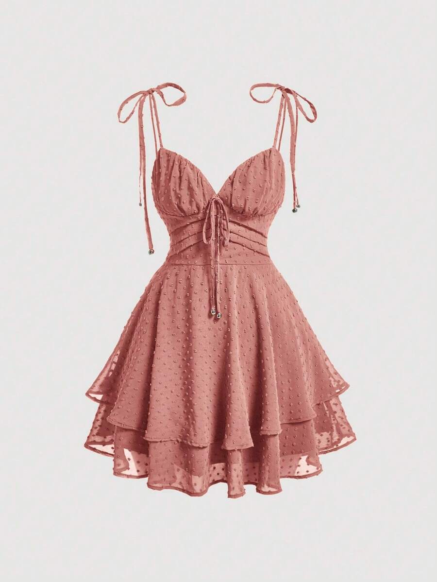 Elevate your wardrobe with this charming Swiss Dot Tie Shoulder Cami Dress. Featuring delicate spaghetti straps, a flattering ruched bust, and a distinctive two-layer tiered hem, this piece effortlessly transitions from casual outings to special occasions. The high-waist silhouette and knot detail at the shoulders add sophisticated touches, while the short length keeps things breezy and modern. Crafted from 100% polyester woven fabric in a rich redwood tone, it's perfect for graduation season