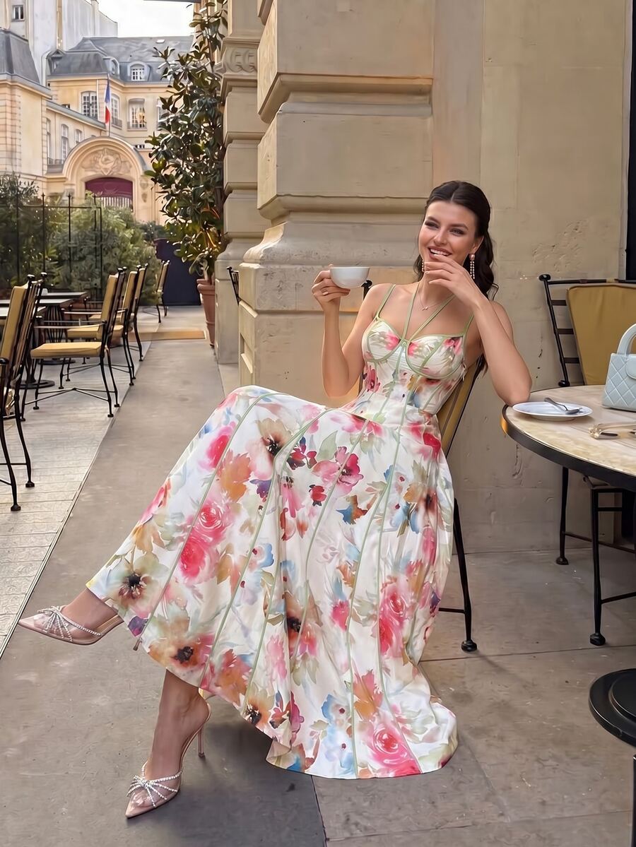 Seated front view of watercolor floral maxi dress with sage piping at an outdoor cafe