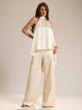 Elevate your warm-weather wardrobe with this sophisticated two-piece set. The halter neck camisole features luxurious white satin that drapes beautifully, while the coordinating pants offer a sleek, tailored silhouette. Perfect for spring and summer occasions—from casual brunches to evening gatherings. The satin finish catches light elegantly, making this set an effortless choice for anyone seeking polished, versatile style. Mix and match with your favorite accessories for endless outfit possibilities.