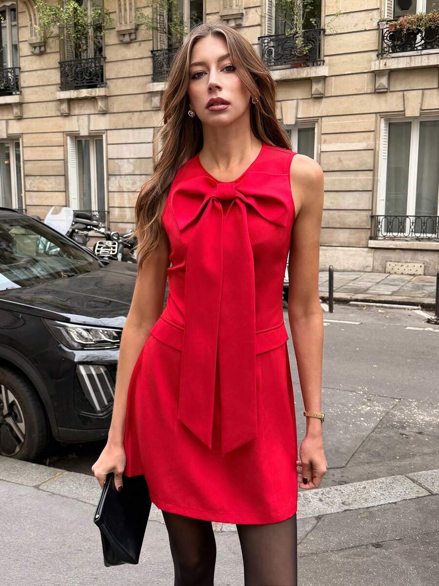 This elegant red sleeveless dress combines timeless sophistication with practical style. Featuring a charming bow detail at the neckline and a flattering fitted silhouette, it's designed for the modern professional. The round neckline and straight hem create a polished look, while the natural waistline offers a classic fit. Crafted from a comfortable polyester-elastane blend, this unlined dress transitions seamlessly from office to evening occasions. The functional zipper closure and decorative knot details