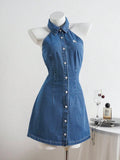 Full front view of medium-wash collared halter mini denim dress with buttons and white chest embroidery
