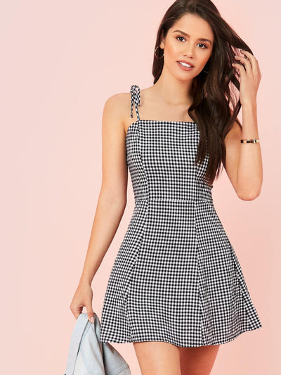 This cami mini dress by Essence of Elegance features a classic gingham print and a self-tie waist, providing a stylish and flattering fit. Made with high-quality materials, this dress is perfect for any occasion, offering both comfort and sophistication. Upgrade your wardrobe with this timeless piece today.