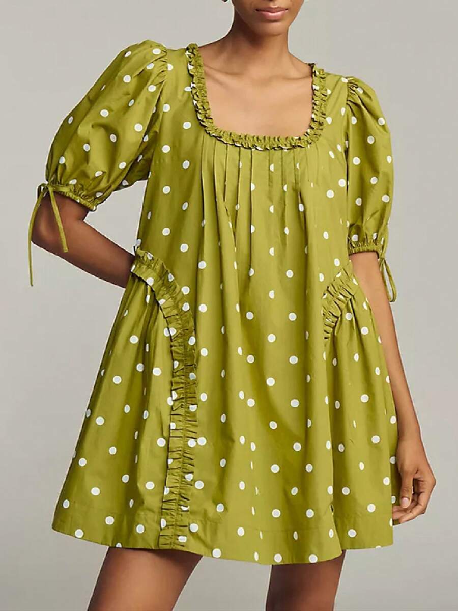 Front three-quarter view of olive polka-dot smock mini dress with ruffled side panels