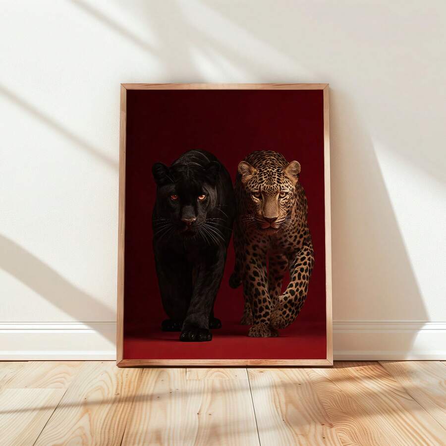 Framed red leopard and black panther wall art leaning on wood floor