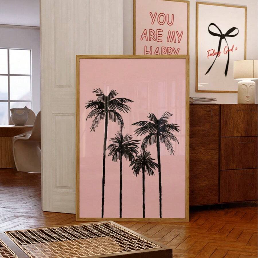 Pink palm tree canvas poster with black tropical silhouettes and gold sun in a modern living room