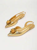 Angled pair view of gold pointed toe slingback flats with jeweled floral ornaments