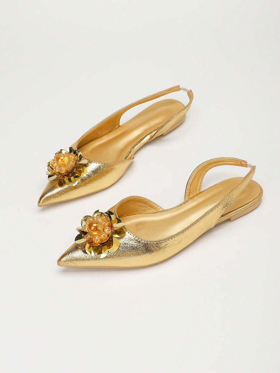 Angled pair view of gold pointed toe slingback flats with jeweled floral ornaments