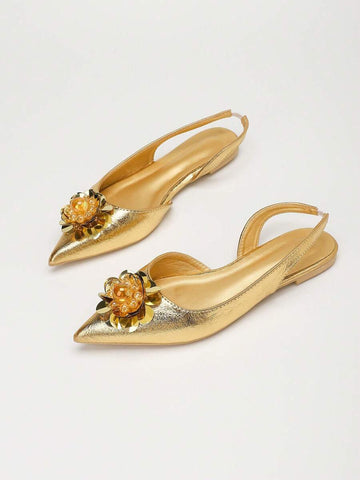 Angled pair view of gold pointed toe slingback flats with jeweled floral ornaments