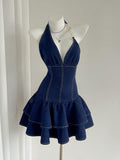 Front mannequin view of dark-indigo halter mini denim dress with gold ring-chain strap and tiered ruffle skirt