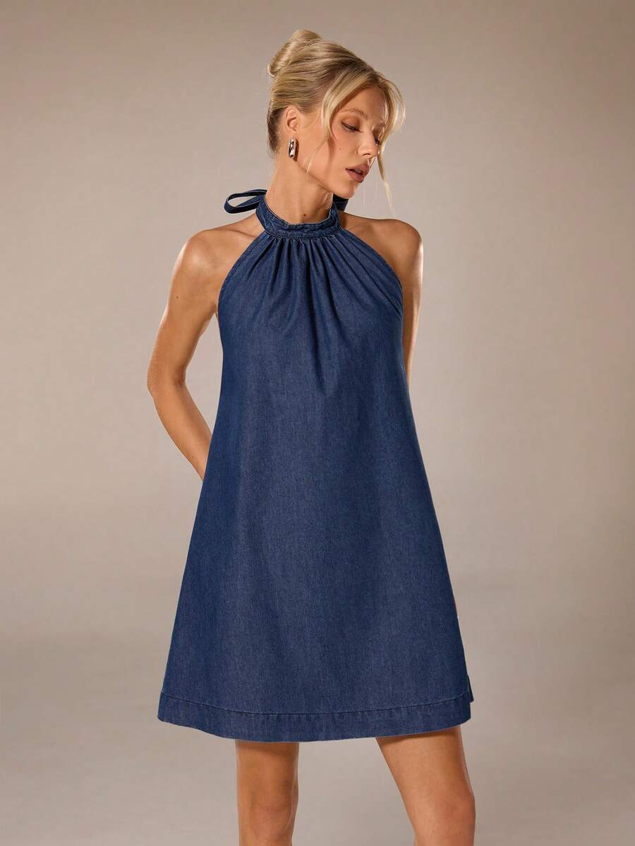 Front view of dark indigo halter denim mini dress with gathered neckline for summer styling