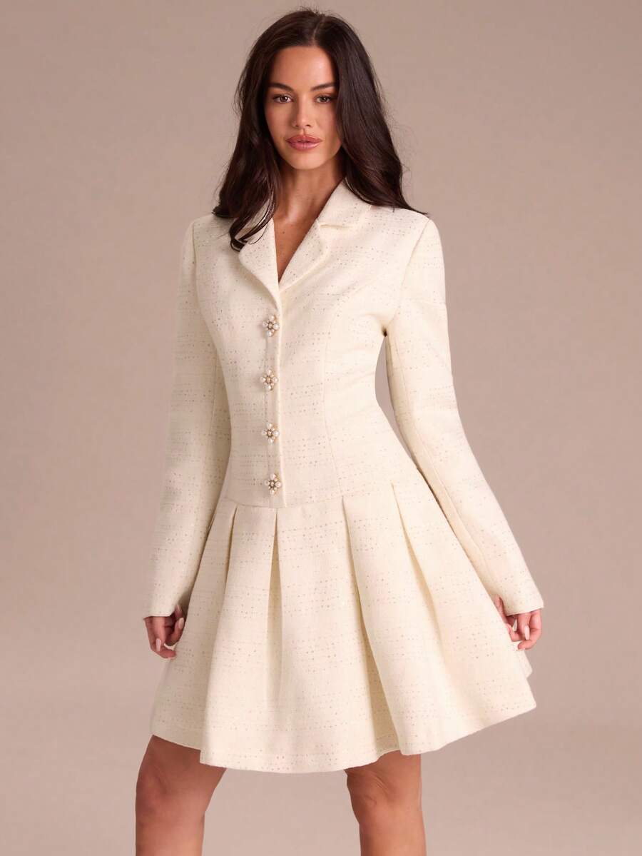 View 1 of ivory tweed long sleeve blazer mini dress with notched collar, pearl floral buttons, subtle sequin check texture, pleated skirt, and back zip