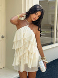 Front view of cream layered ruffle halter mini dress for vacation styling