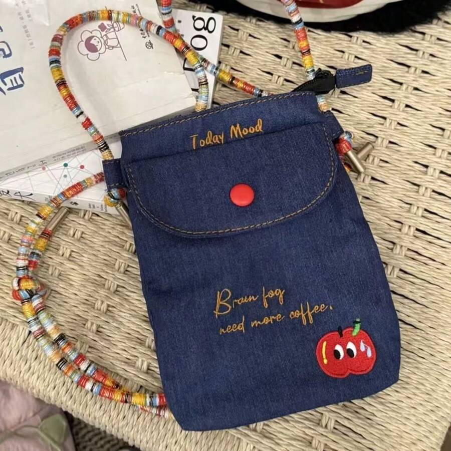 Front angle view of navy denim crossbody phone pouch with red snap and colorful cord strap