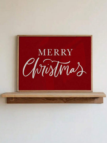 Red canvas wall art reading “MERRY Christmas” in white serif and cursive lettering, displayed in a light wood frame above a console shelf