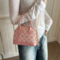 Pink shell shaped crossbody mini bag worn with gold chain strap and monogram print