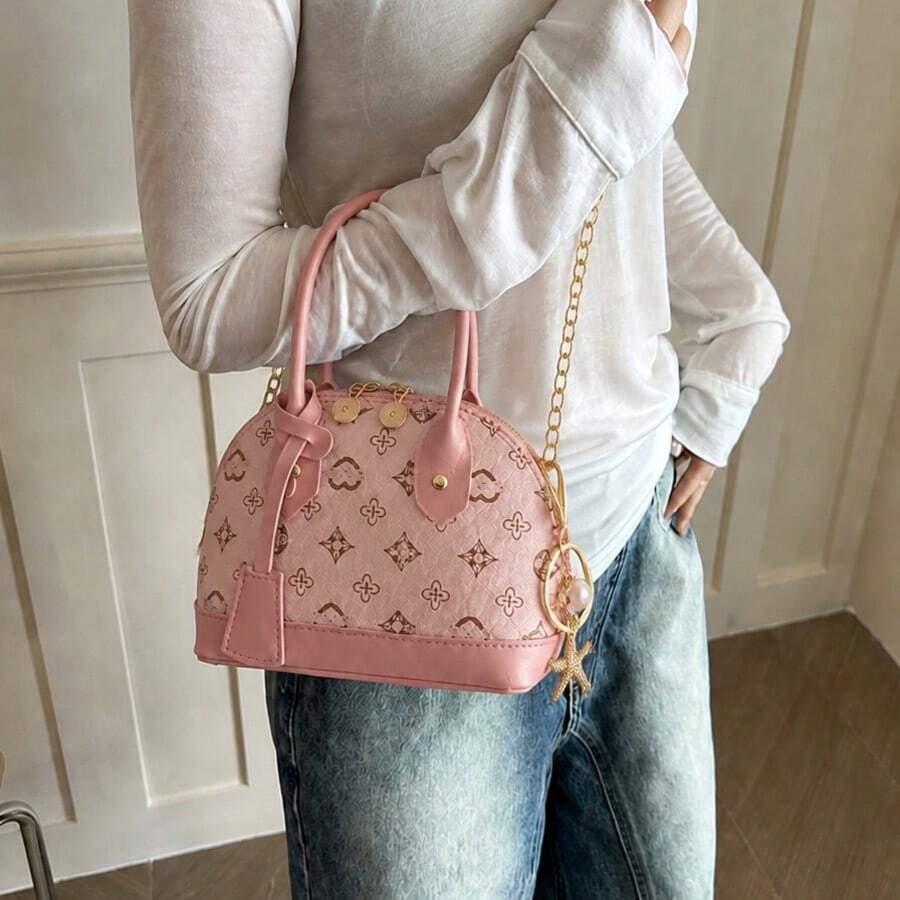 Pink shell shaped crossbody mini bag worn with gold chain strap and monogram print