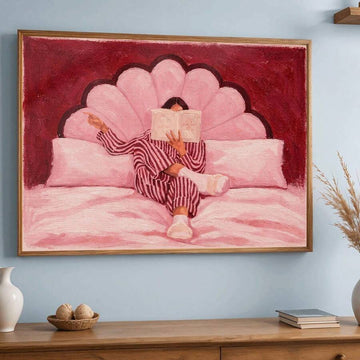 Front view of pink woman reading canvas art in brown frame above a wood cabinet
