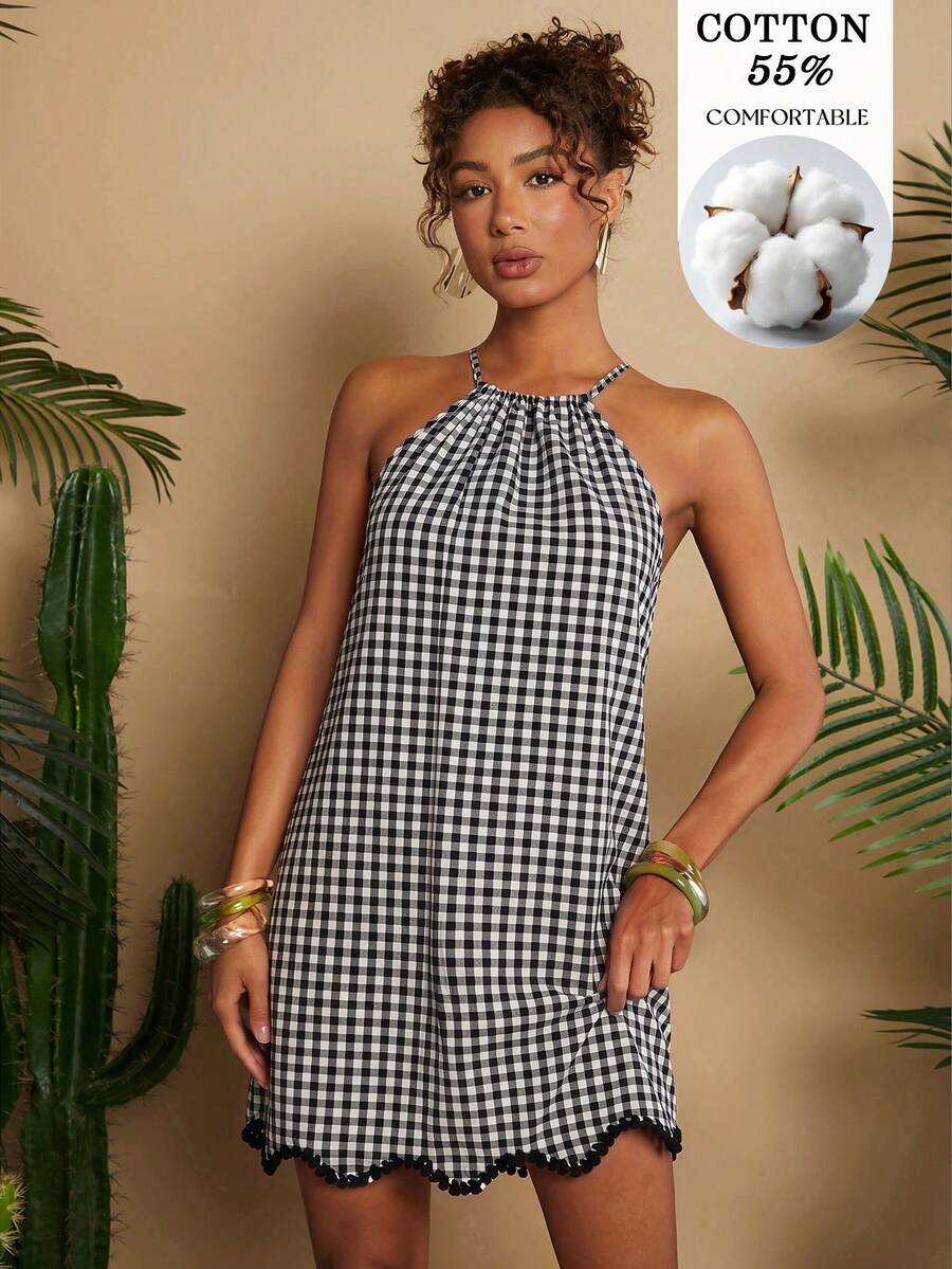 Front view of black and white gingham halter mini dress with pom-pom hem in tropical studio