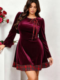 Front view of burgundy velvet plus-size party dress with long sleeves, tartan neckline bow and plaid flared hem