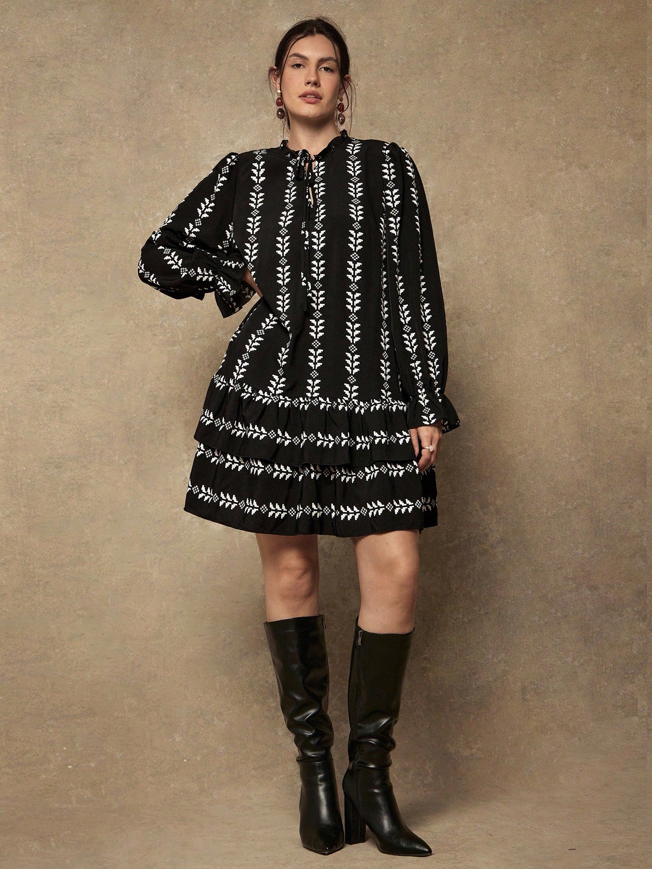 Make a statement with this playful plus-size dress that brings together bold geometric prints and charming details. The tie collar adds a flirty touch while long sleeves provide comfortable coverage, perfect for transitioning between seasons. A ruffled hem gives you that extra dash of personality and movement. Whether you're heading to brunch or a casual day out, this dress celebrates your curves with style and confidence. Effortlessly chic and undeniably fun.