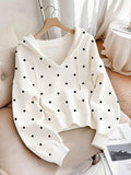 Front view of white polka dot hoodie with drawstring hood and pouch pocket in indoor setting