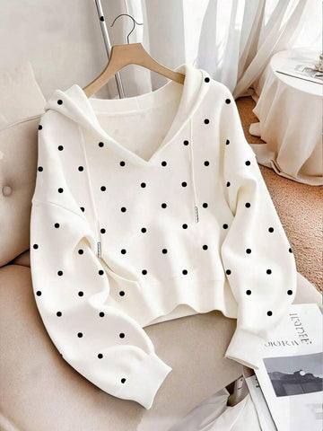 Front view of white polka dot hoodie with drawstring hood and pouch pocket in indoor setting