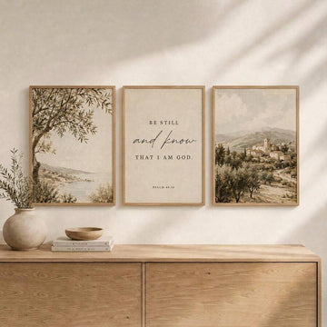 Framed three-panel gallery wall showing olive tree shoreline, Psalm 46:10 scripture, and muted village landscape above a console