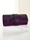 Purple embellished evening clutch on marble surface with curved flap and central rhinestone strap