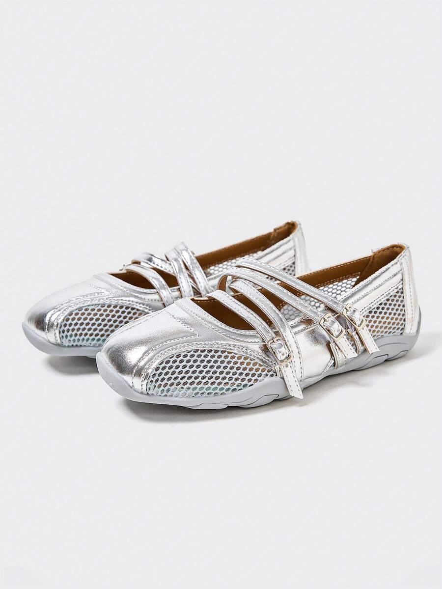 Front three-quarter view of silver three-strap Mary Jane flats with mesh panels and segmented sole