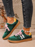Side view of green colorblock stripe sneakers with pink laces and flat brown gum soles