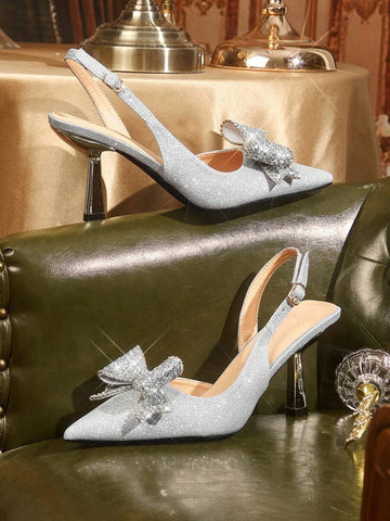 pair of silver glitter pointed-toe slingback pumps with rhinestone bows