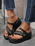 Black platform thong sandals worn on foot showing open heel and shiny instep straps