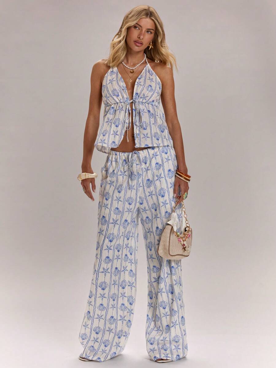 Dive into summer style with this eye-catching seashell print two-piece set. The tie-up halter top features a flattering neckline and adjustable fit, while the wide-leg pants offer effortless comfort and movement. Perfect for beach days, tropical getaways, or casual seaside strolls. The coordinated print creates a cohesive, fashion-forward look that transitions seamlessly from sand to dinner. Lightweight fabric keeps you cool in warm weather. 