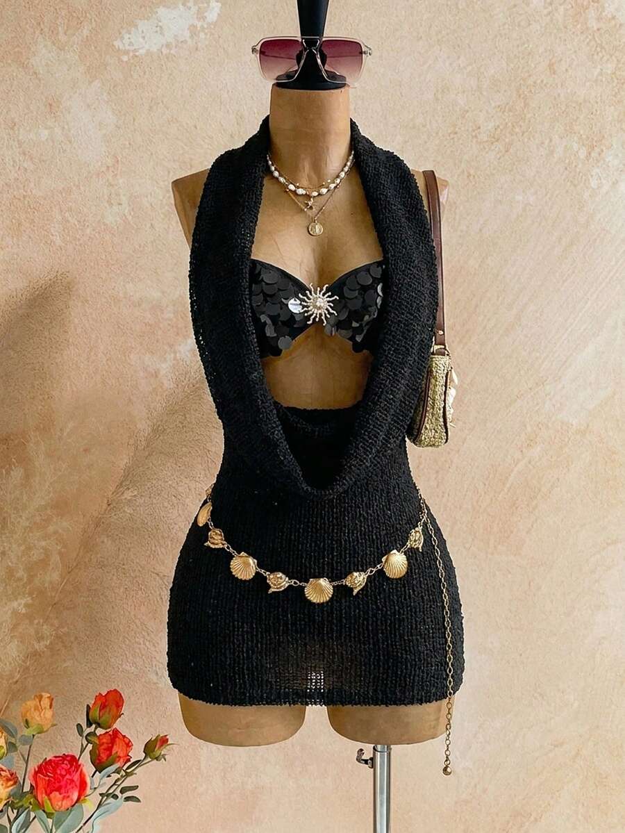 Black open-weave hooded mini dress on mannequin with black sequin shell bra, gold sunburst hardware, shell chain belt