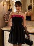 Front view of black strapless mini party dress with dimensional rose trim and flared skirt