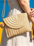 On-body front view of beige straw woven envelope crossbody bag with pom-pom charm