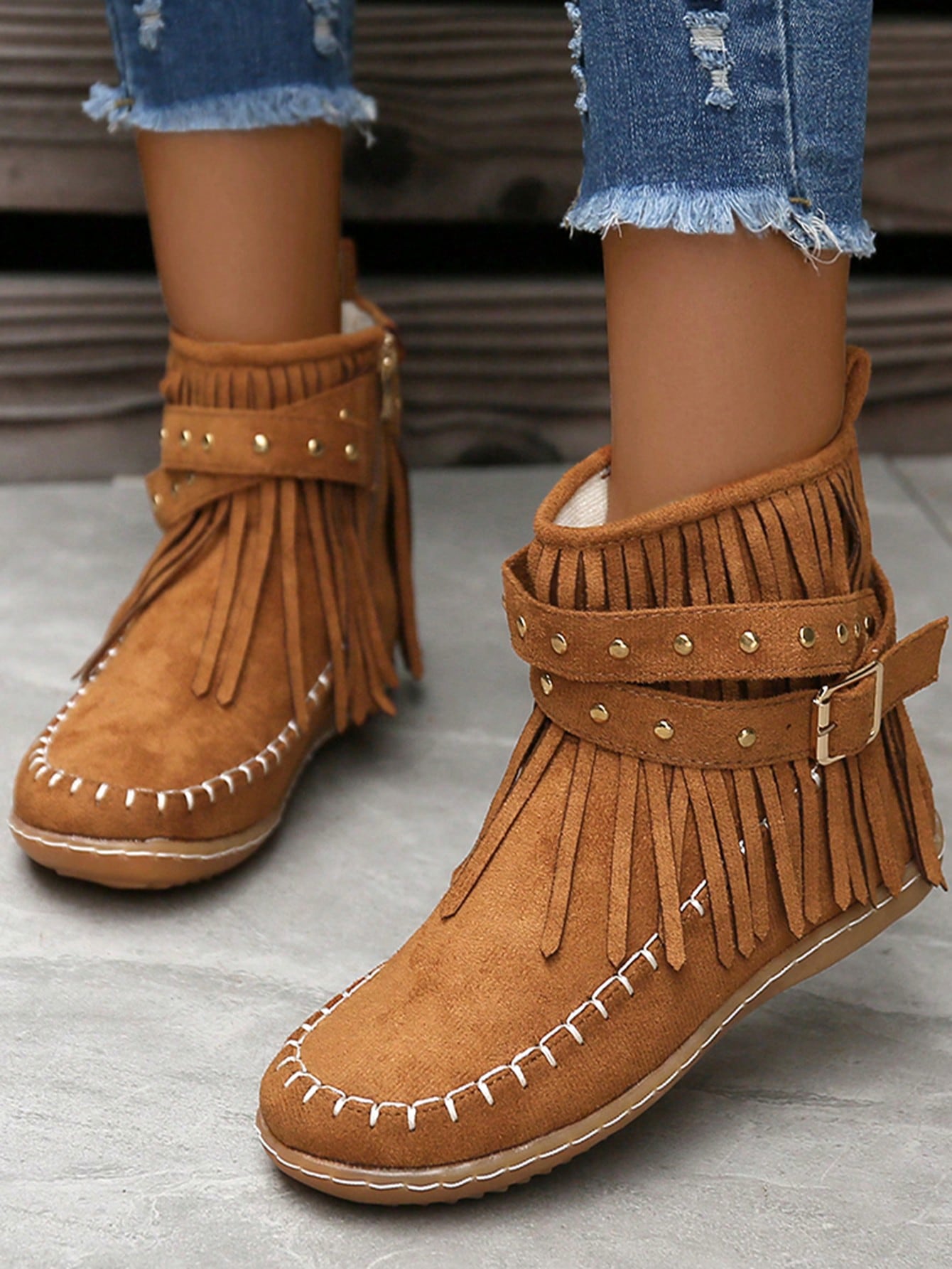 Perfect for adding some edge to your wardrobe, these stylish flat boots feature a unique combination of studs and fringe detailing. With a classic round toe design and convenient side zipper, these boots are both fashionable and functional. Take your outfit to the next level with these statement-making boots.